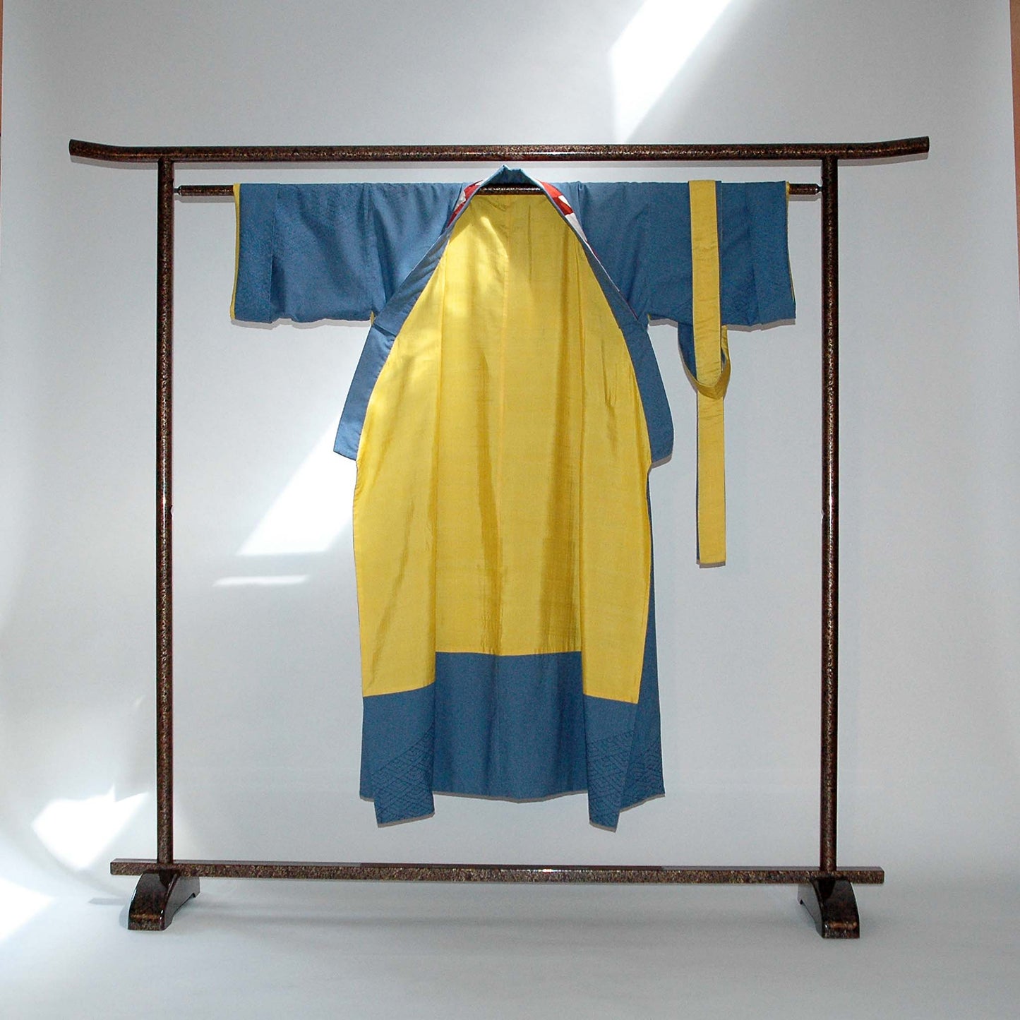 Kimono-Raritaet Sashiko. Der geöffente Kimono gibt die zweite Seite aus erfrischender, gelben Seide preis. Das diagolnale Band der Sashiko-Stickerei umwindet den ganzen Kimono von Design Gianni Sarto