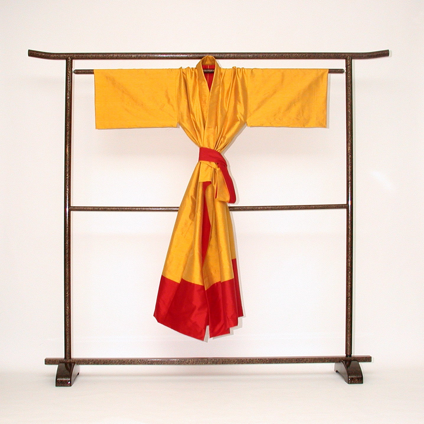 Auf einem japanischen Kimono-Ständer ein Seiden-Kimono. Er ist  wendbar, gefertigt in sonnengelber und roter  Doupion-Seide. Handgefertigt Design Gianni Sarto Made in Germany